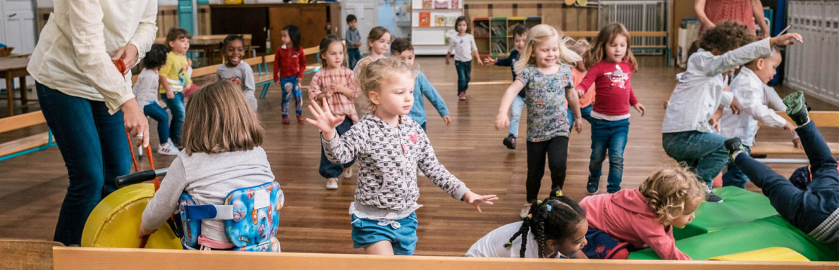 Une petite fille handicapée à la crèche entourée d'autres enfants.